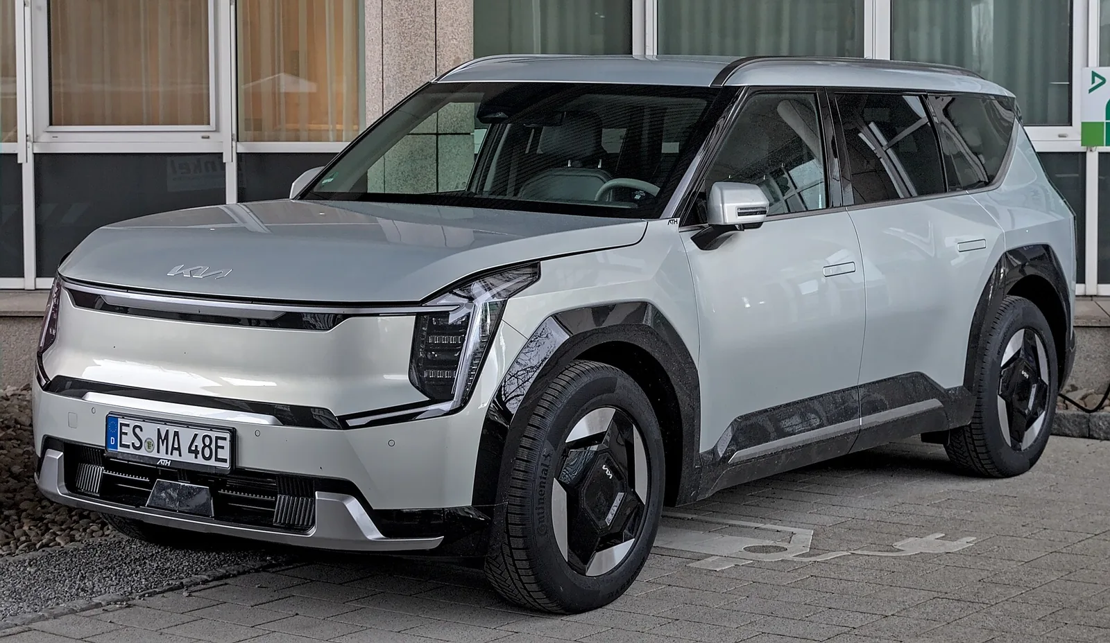 Silver Kia EV9 three-row electric SUV parked in Stuttgart, seen from the front three-quarter angle.