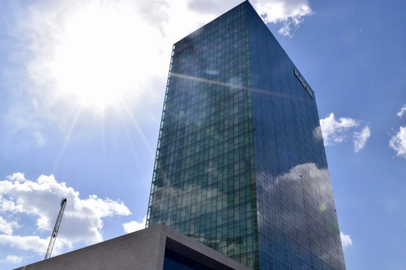 NAVER Green Factory, the glass headquarters tower of NAVER in Seongnam, under a bright blue sky.