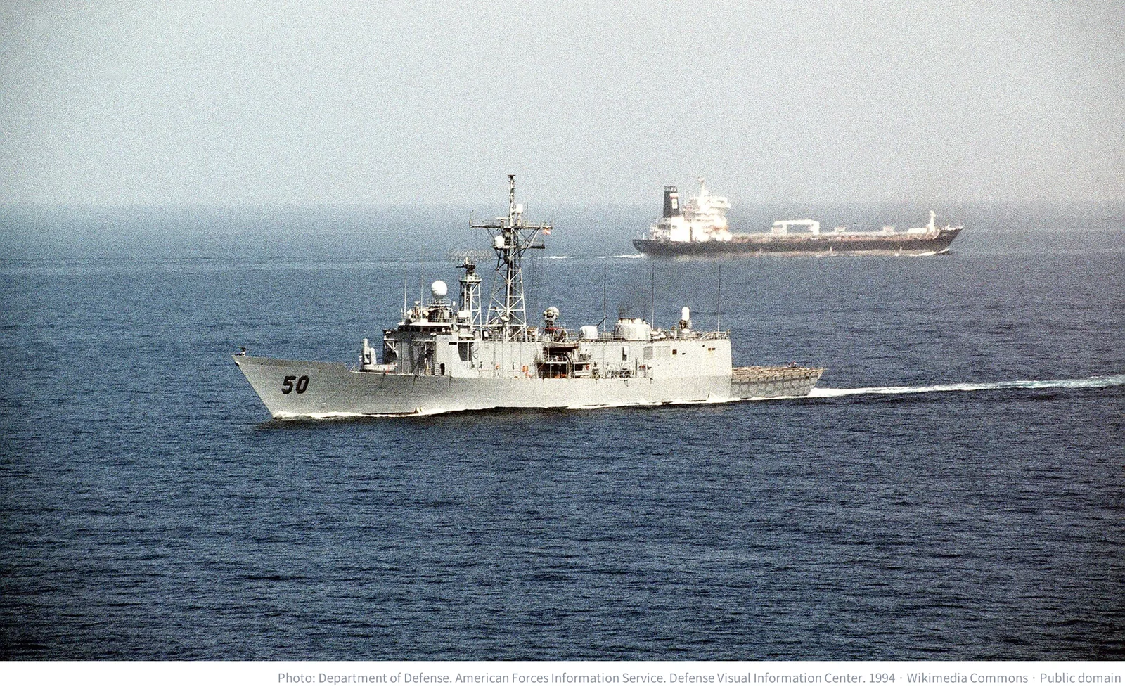 A U.S. Navy frigate passing an oil tanker after transiting the Strait of Hormuz